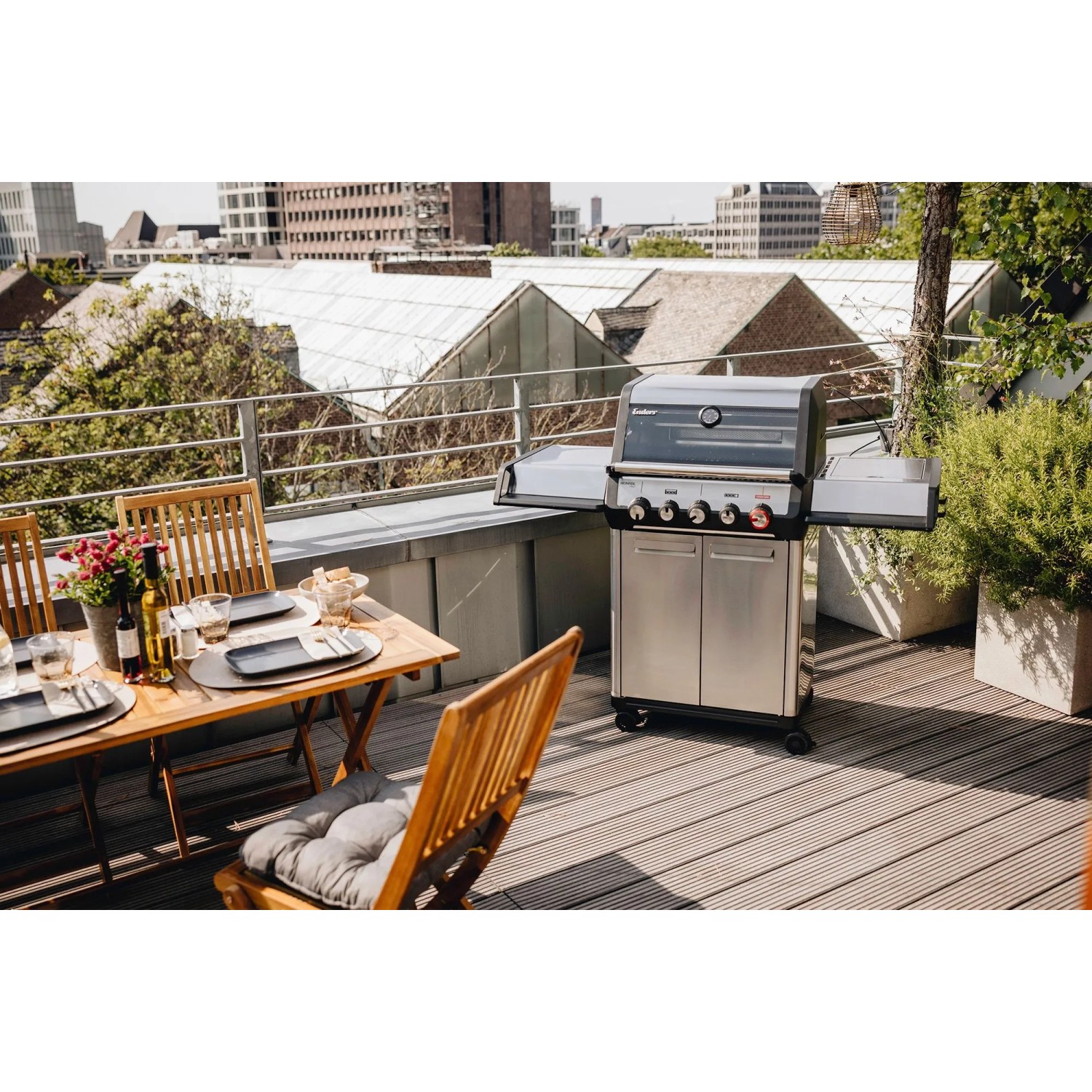 Enders Gasgrill Monroe Pro 3 SIKR Turbo auf einer Dachterrasse mit Tisch und Stühlen.