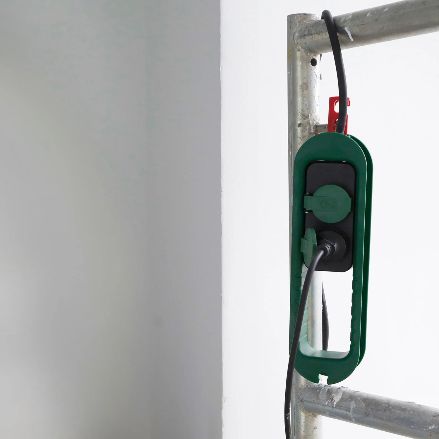 Grün-schwarze 2-fach Steckdosenleiste IP44 mit Kabelaufwicklung am Gerüst.