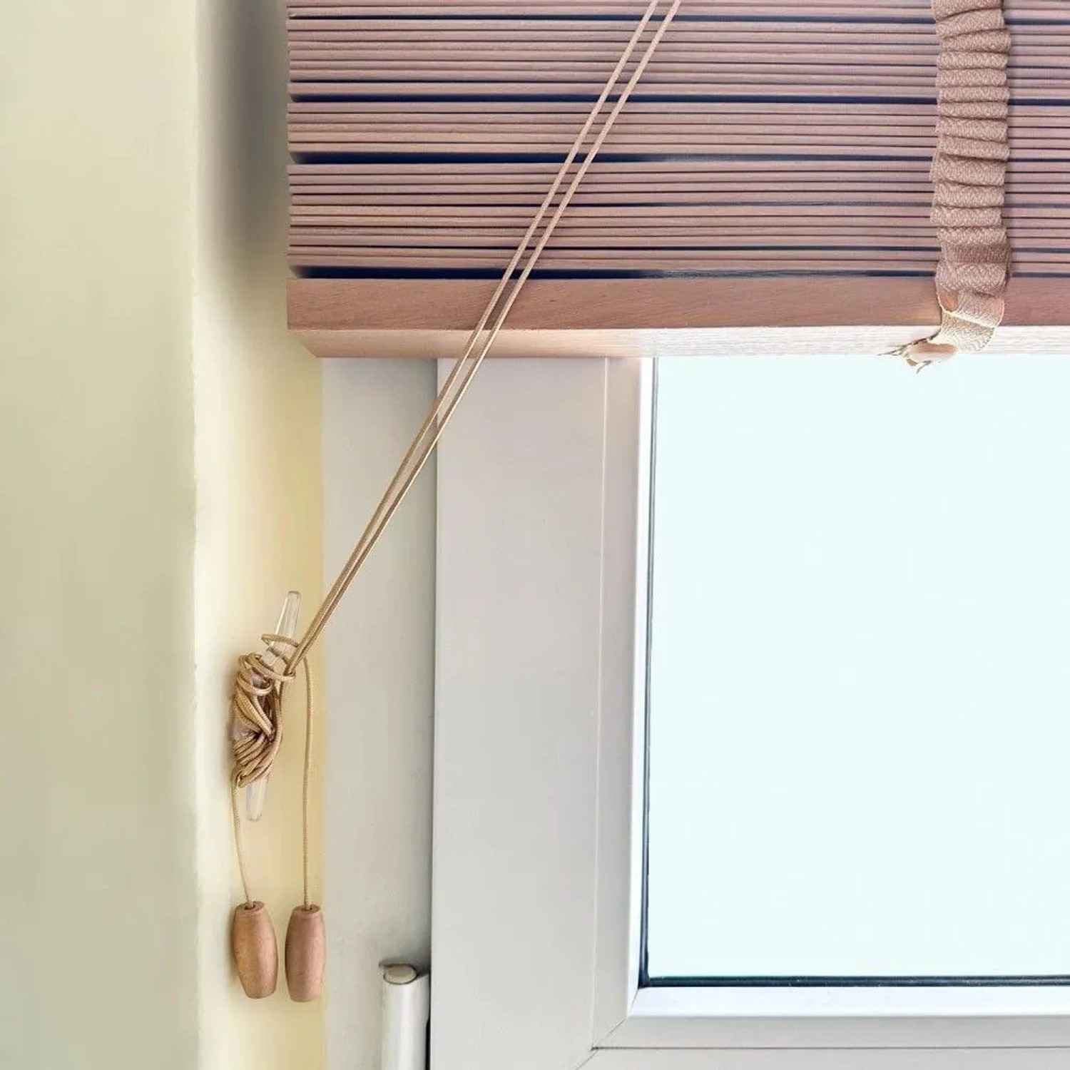 Schwarze Sol Royal Holzjalousie (B130xH250cm) am Fenster mit Zugschnüren.