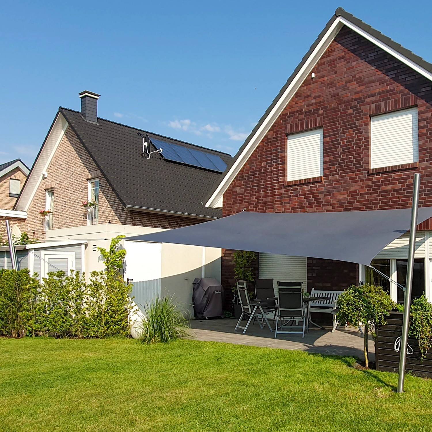 Quadratisches, anthrazitfarbenes Toldoro Sonnensegel spendet Schatten auf Terrasse mit Gartenmöbeln.