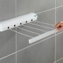 Wenko Wand-Wäscheleine, ausziehbar, weiß, mit fünf Leinen und Hand die Leine hält.