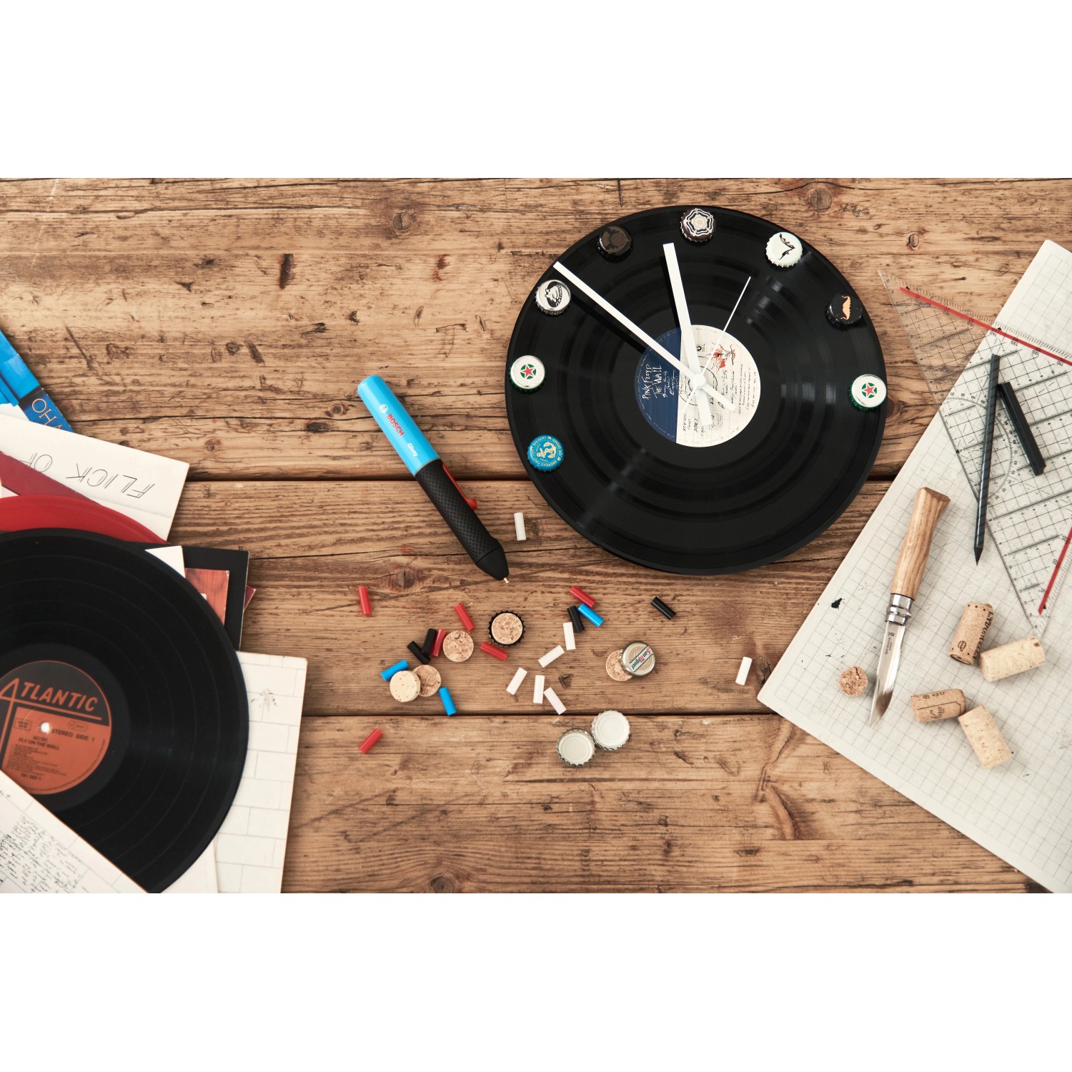 Bosch Gluey Lagoon Blue Heißklebestift auf Werkbank mit Vinyl-Uhr und Bastelmaterial.