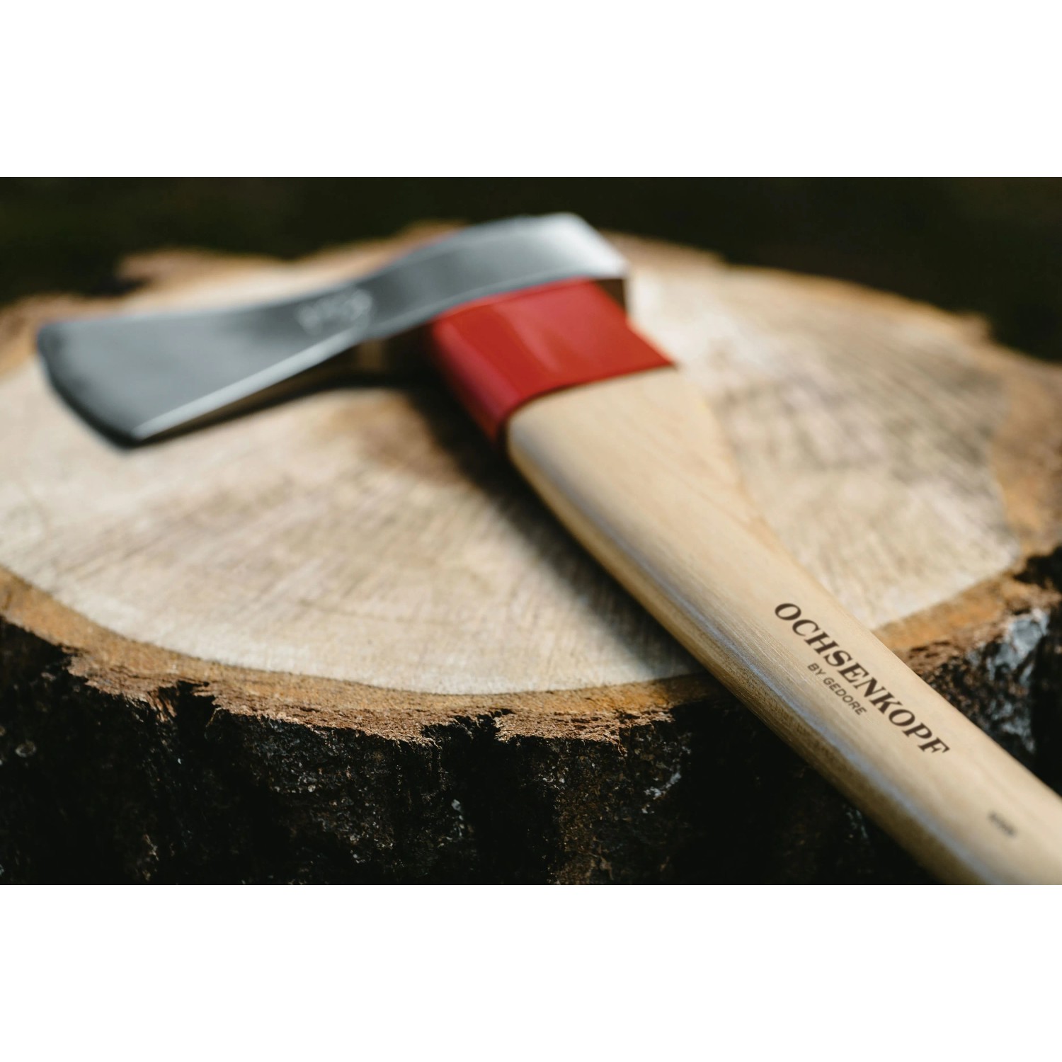 Ochsenkopf Forstaxt Universal Gold mit poliertem Kopf, roter Stielschutzhülse und Hickory-Stiel auf Holzstamm.
