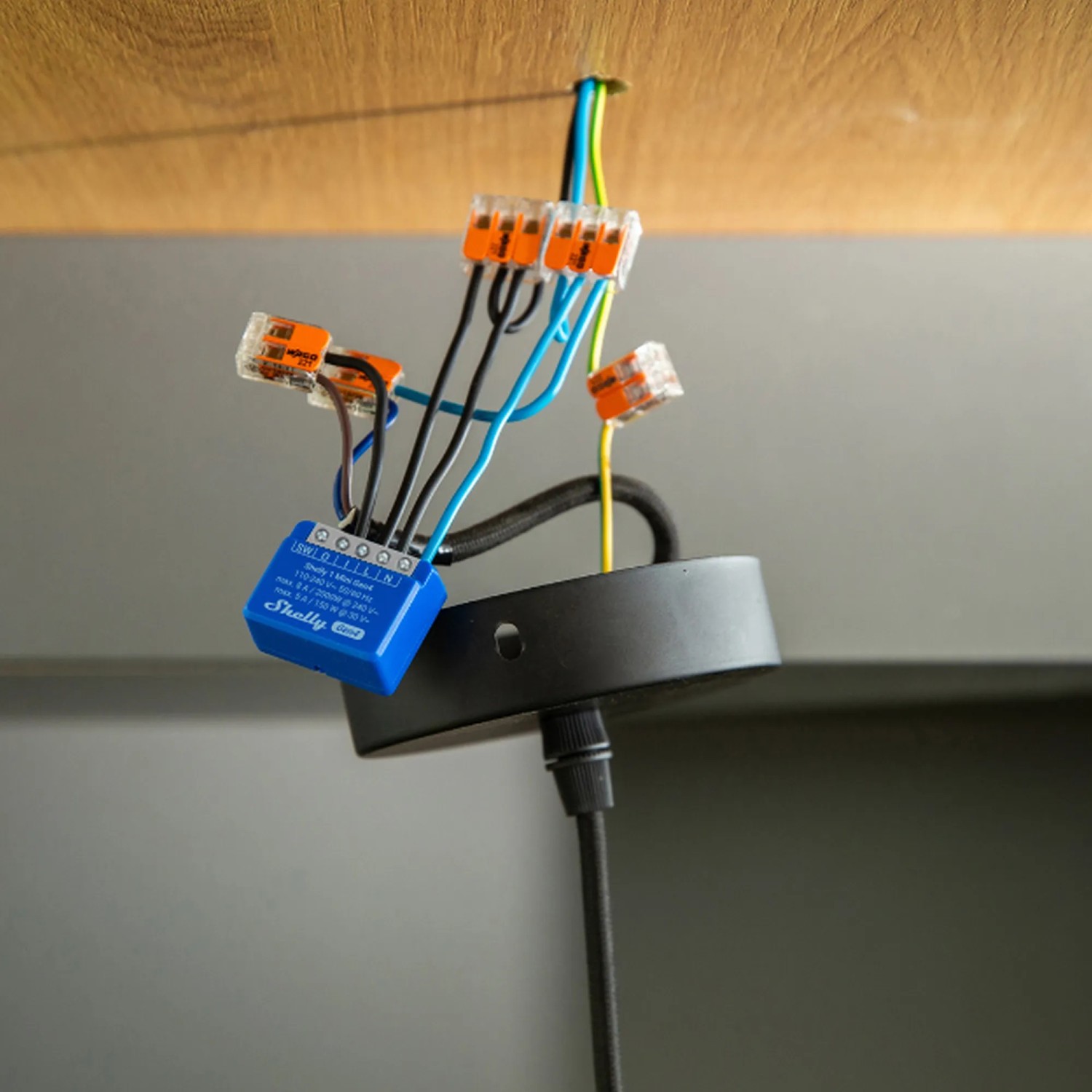 Blaues Shelly Smart-Relais Mini Gen4 Unterputz mit Verkabelung an Lampe montiert.