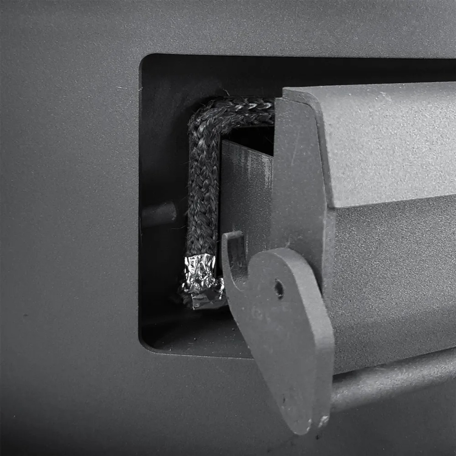 Detailansicht des Kaminofen Türverschlusses mit geflochtener Dichtung und robustem Metallhaken.