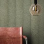 Newroom Vliestapete Kihmo Green mit Streifenmuster, kombiniert mit Lampe und Stuhl.