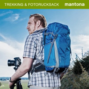 Mann trägt blauen Mantona Outdoor Fotorucksack beim Trekking. Kamera auf Stativ im Freien. Praktische Aufbewahrung.