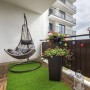 Kunstrasen Riviera auf Balkon mit Hängekorb-Sessel und Pflanzen. Wetterfest und UV-beständig.