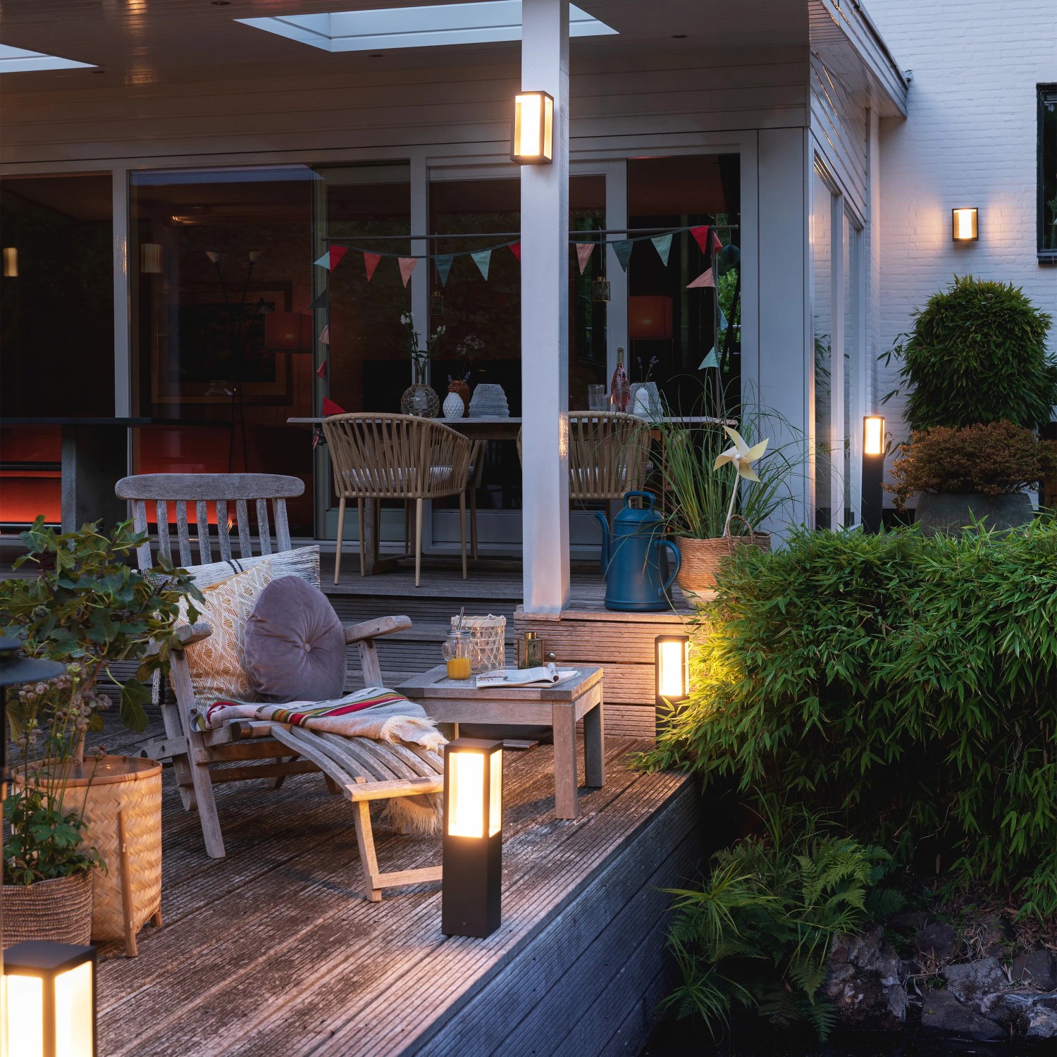Philips Hue Impress: Schwarze LED-Wandlampe mit Farbwechsel für den Außenbereich, montiert an Hauswand und als Wegeleuchte.