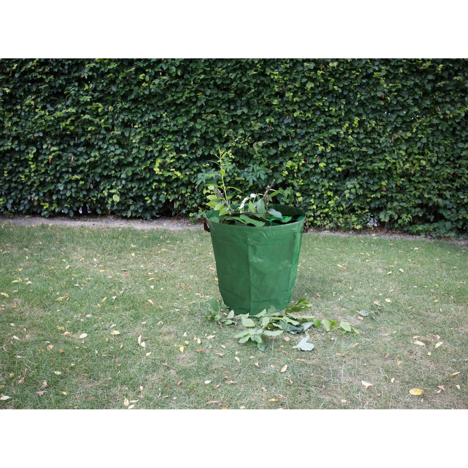Grüner Gartenabfallsack (265 l) aus Polypropylen, gefüllt mit Gartenabfällen auf einer Rasenfläche.