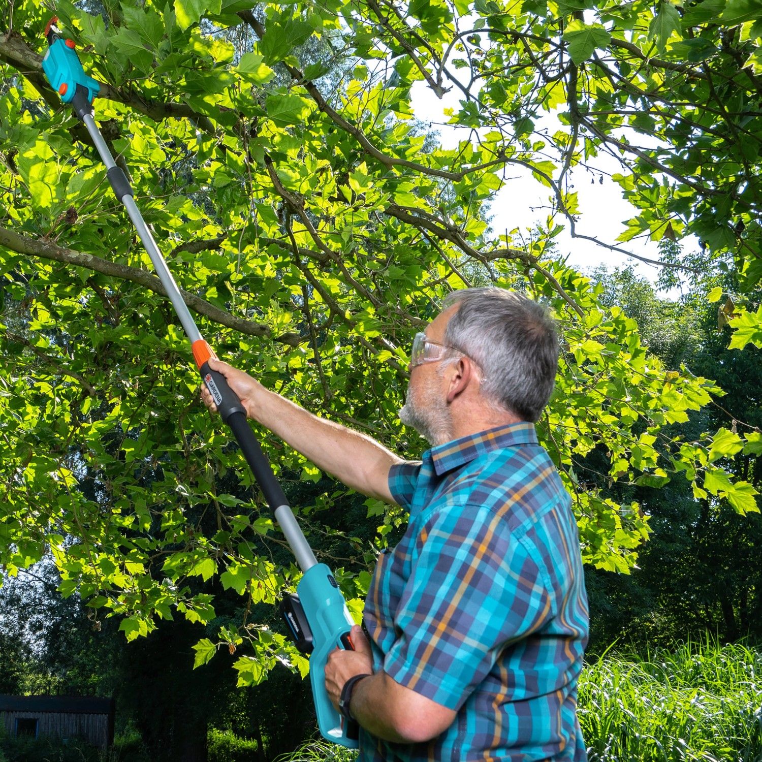 Mann schneidet Äste mit Gardena Akku-Teleskop-Hochentaster TCS 20/18V im Garten.