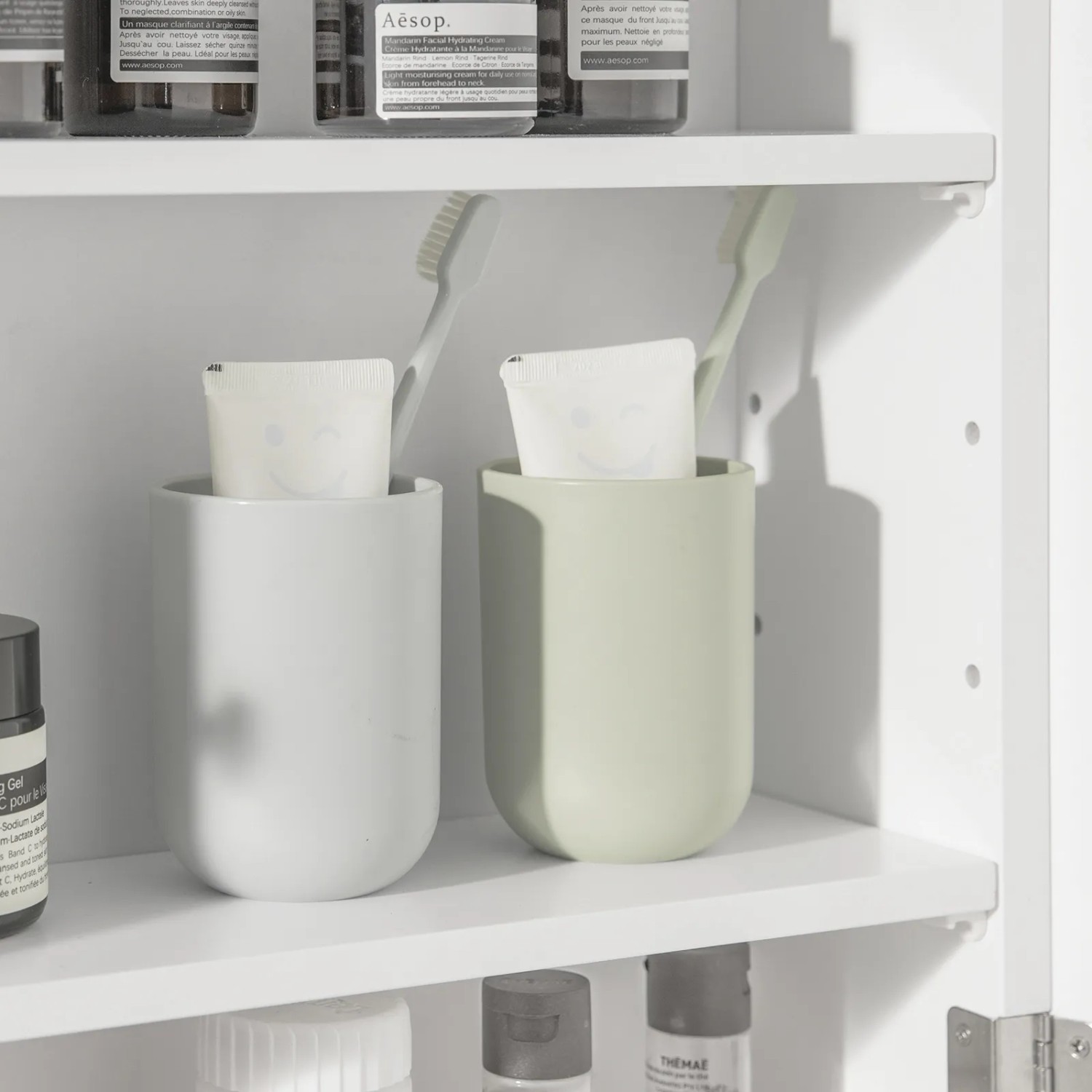 Detailaufnahme: Weißer SoBuy Spiegelschrank (BZR55-W) mit Lamellentür, Ablage mit Badutensilien.