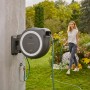 Gardena Akku-Wand-Schlauchbox PowerRoll XL mit 35m Schlauch im Garten mit Frau.
