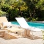 Weiße Beliani Gartenliege (65x198x107) mit verstellbarer Rückenlehne und Rollen vor Pool.