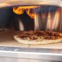 Buschbeck Pizzaofen X1 mit Pizza im Ofen unter Flammen.