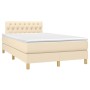 Cremefarbenes Boxspringbett 120x200 cm mit Stoffbezug und gestepptem Kopfteil.