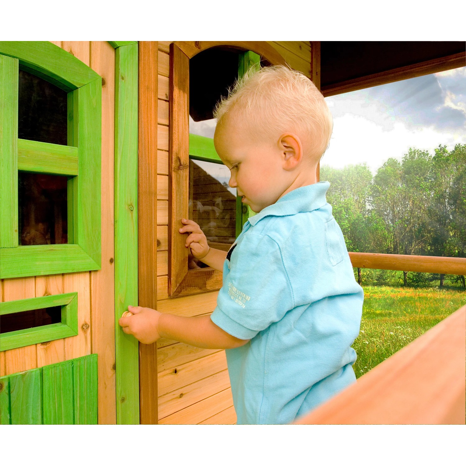 Kind öffnet Fenster vom Spielhaus Laura mit Leiter und Rutsche. Holzhaus mit grünen Akzenten.