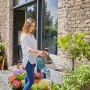 Frau bewässert Pflanzen mit Gardena Spiralschlauch-Set (10 m) im Garten.