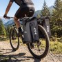 Schwarze Wiltec Doppeltasche am Fahrrad-Gepäckträger eines Mountainbikes auf Waldweg. Wasserfeste Fahrradtasche mit 48L Stauraum.