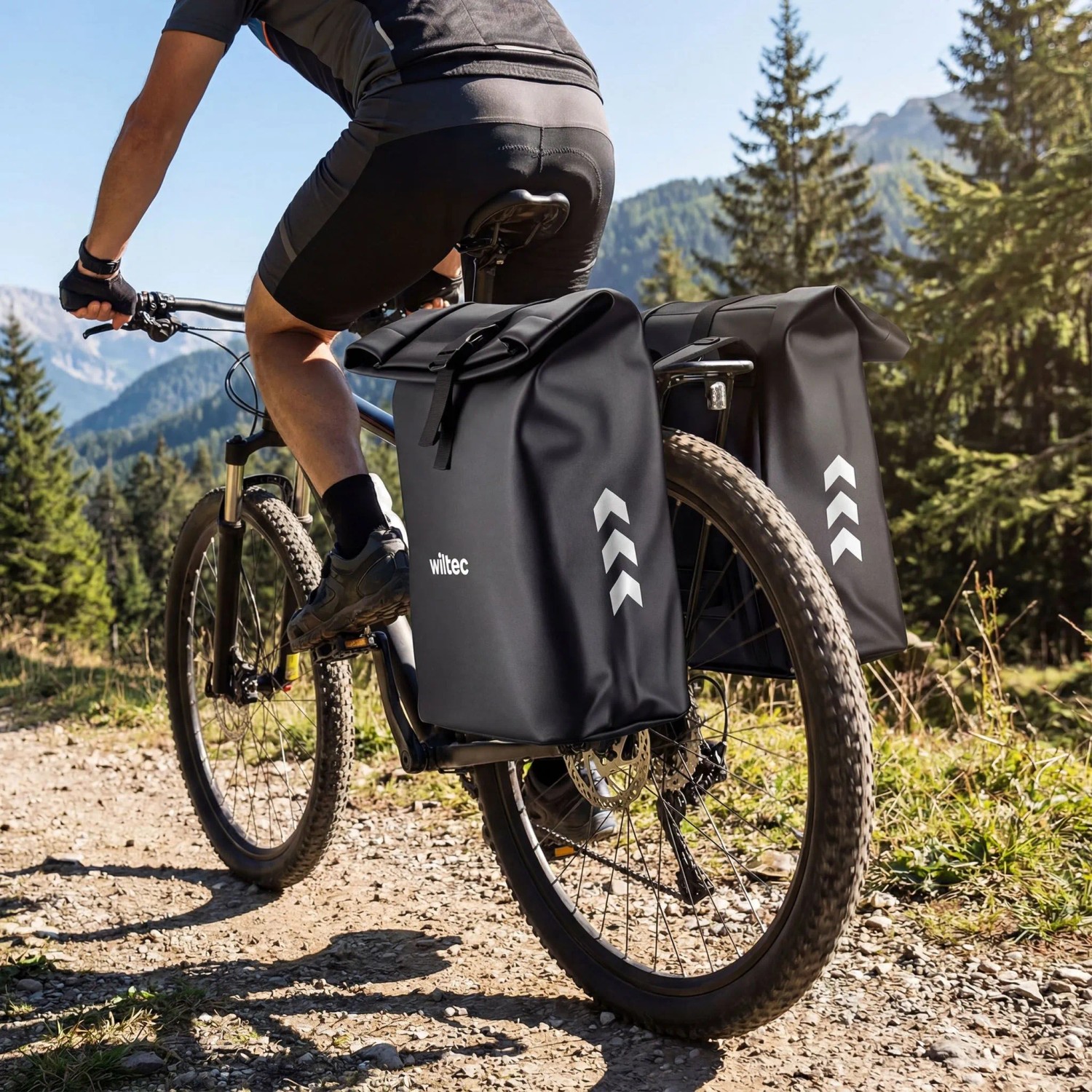 Schwarze Wiltec Doppeltasche am Fahrrad-Gepäckträger eines Mountainbikes auf Waldweg. Wasserfeste Fahrradtasche mit 48L Stauraum.