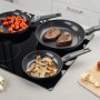 Fackelmann Bratpfannen Set auf Induktionsherd mit Gemüse und Fleisch.
