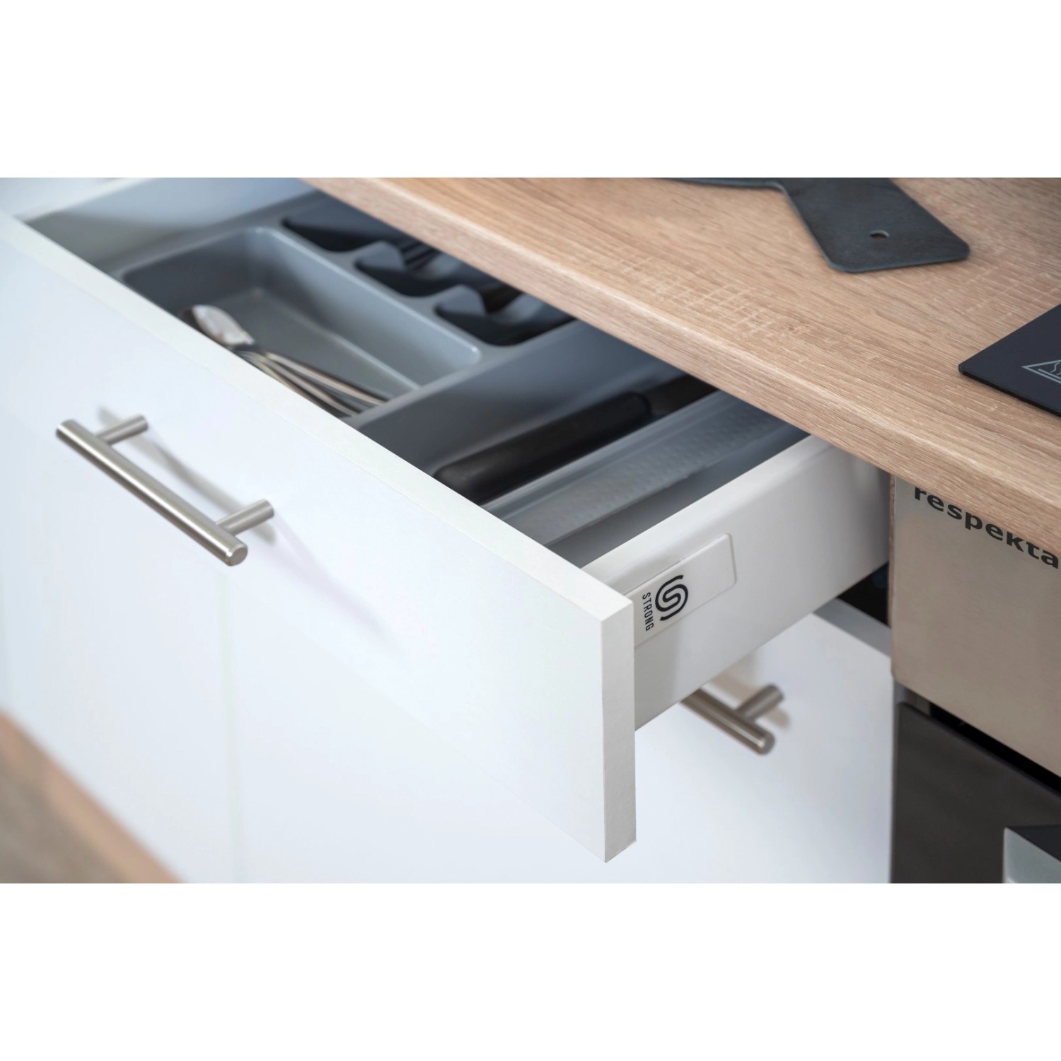 Offene Schublade der Respekta Küchenzeile in Weiß-Eiche mit Besteckkasten.