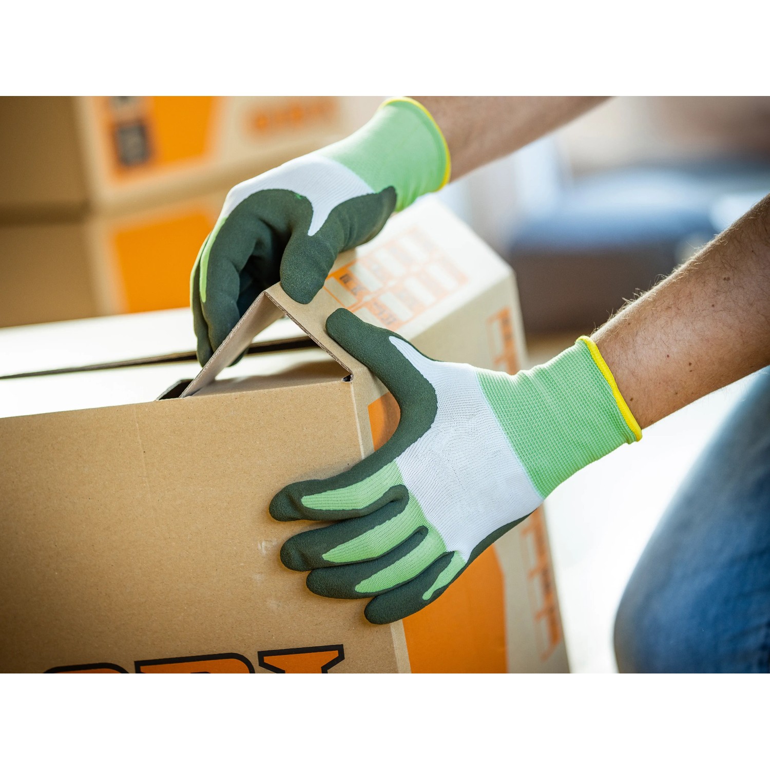 Hände mit LUX Arbeitshandschuhen Eco Gr. 10 beim Falten eines Kartons.