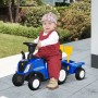 Kleinkind fährt blaues HOMCOM NEW HOLLAND Rutschauto Traktor mit Anhänger und Spielzeug im Garten. Ideal als Laufhilfe.