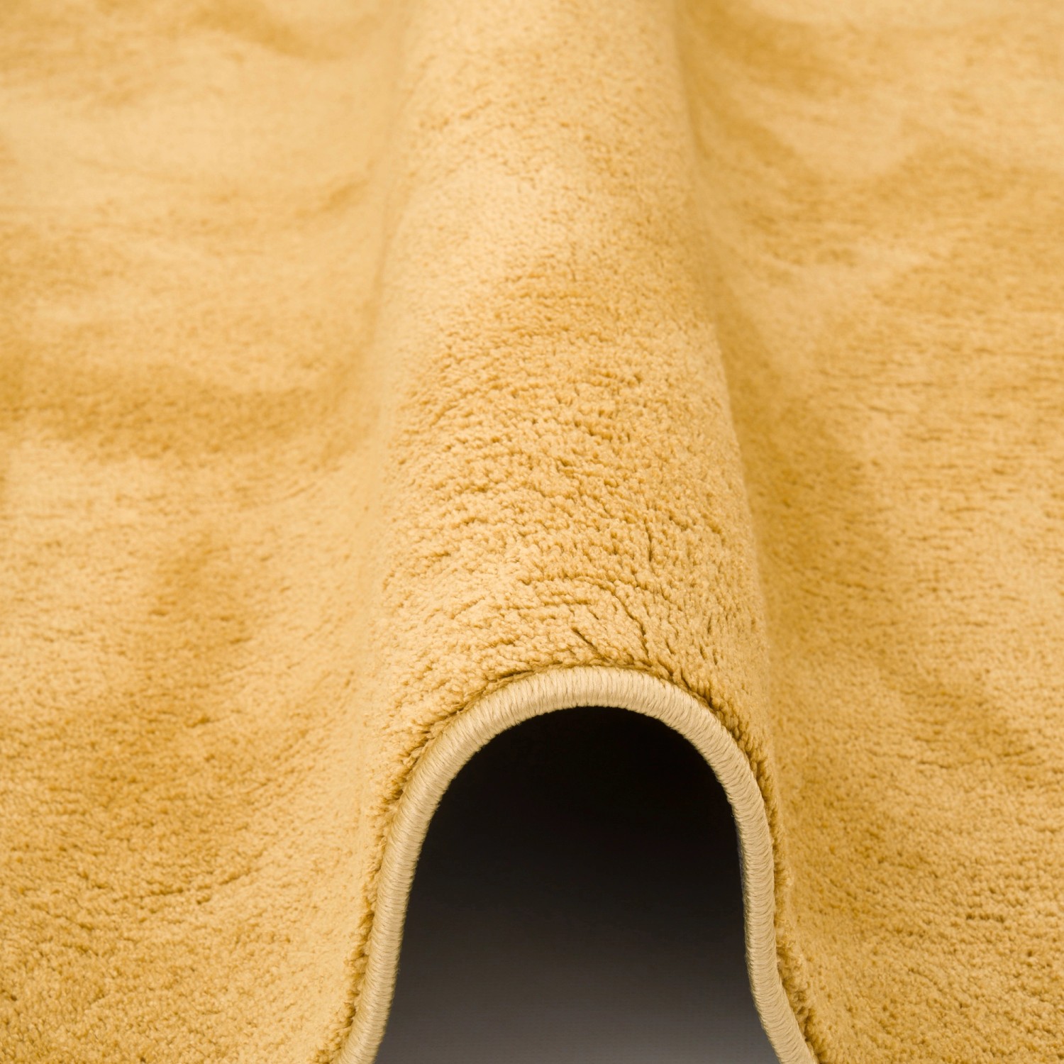 Detailansicht: Curryfarbener Pergamon Hochflor Teppich (80x150cm) mit weicher Textur.