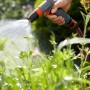 Hand hält Gardena Comfort Reinigungsspritze, Wasserstrahl ist sichtbar.