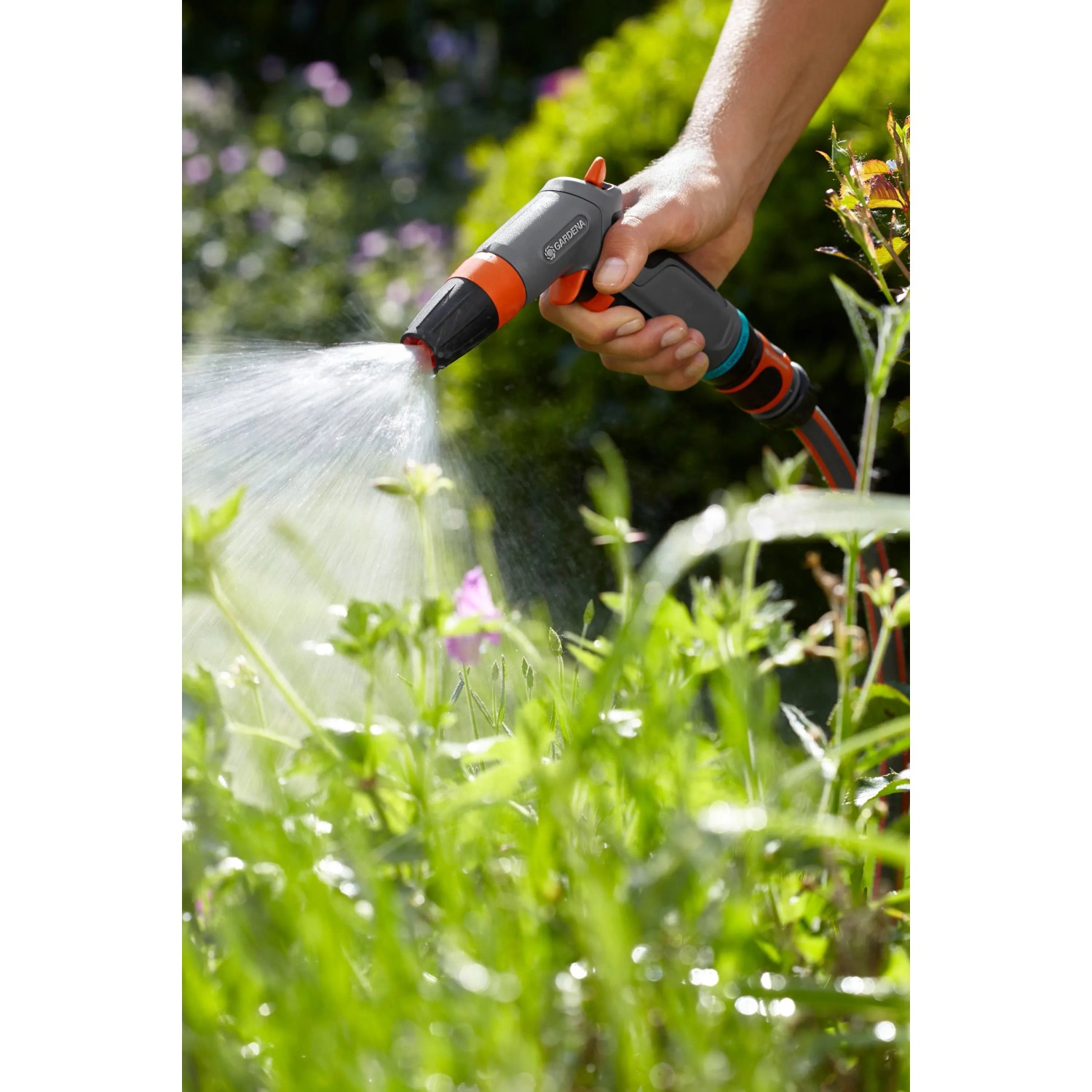 Hand hält Gardena Comfort Reinigungsspritze, Wasserstrahl ist sichtbar.