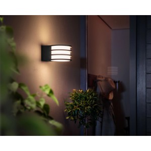 Anthrazitfarbene Philips Hue LED-Wandleuchte Lucca mit warmweißem Licht an Hauswand.