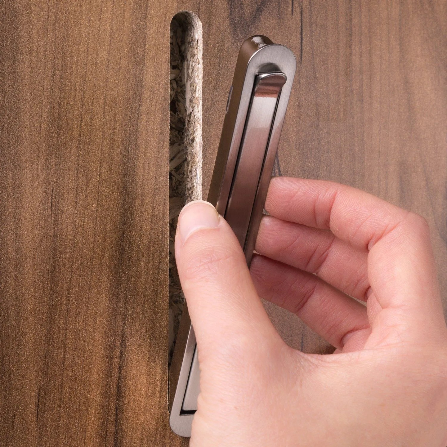 Hand setzt SOTECH Klapphaken ZILLY Chrom matt in gefräste Holzplatte ein. Garderobenhaken zum Einfräsen.
