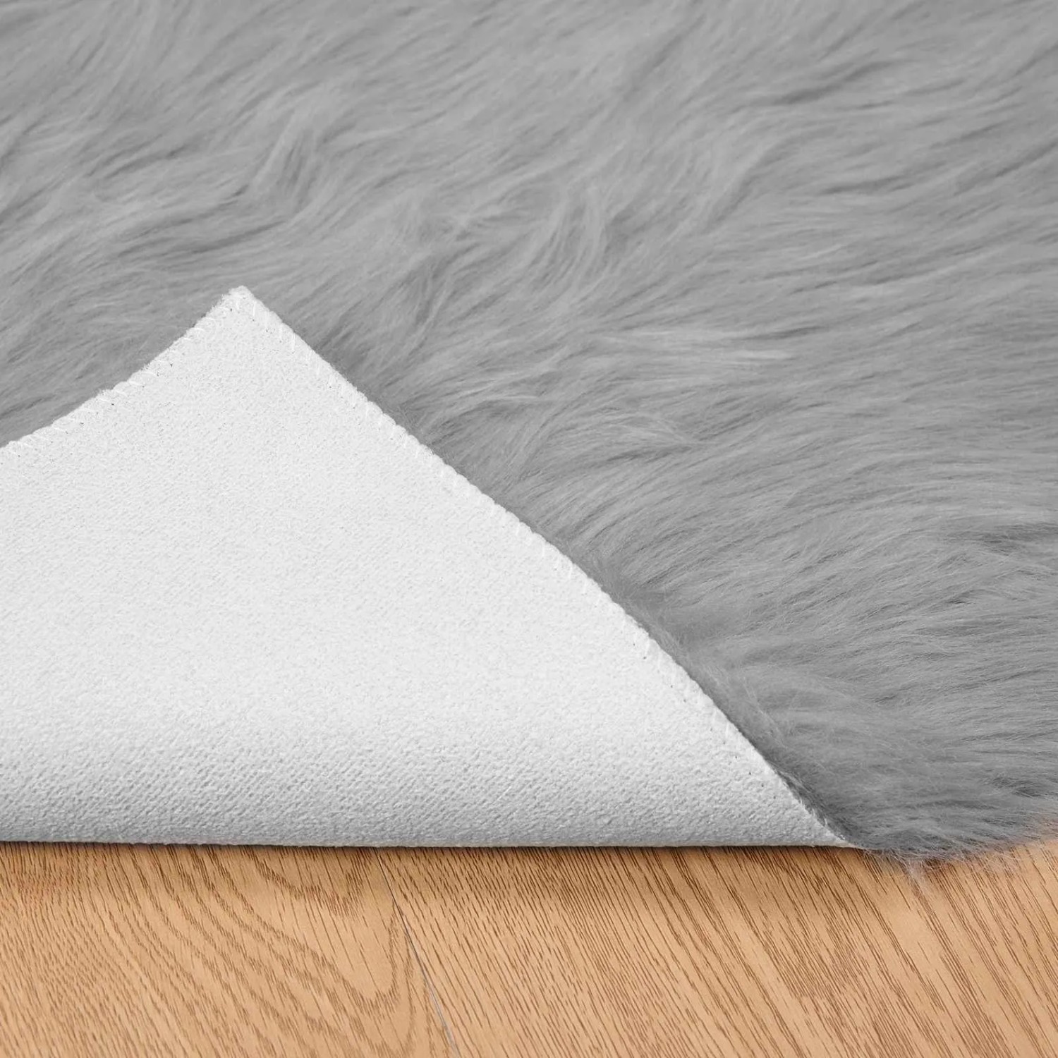 Grauer vidaXL Kunstschaffell Teppich (140x200 cm) mit weißer Rückseite auf Holzboden.