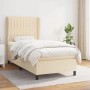 Cremefarbenes Boxspringbett (90x190 cm) mit Matratze und hohem Kopfteil. Stoffbezug.