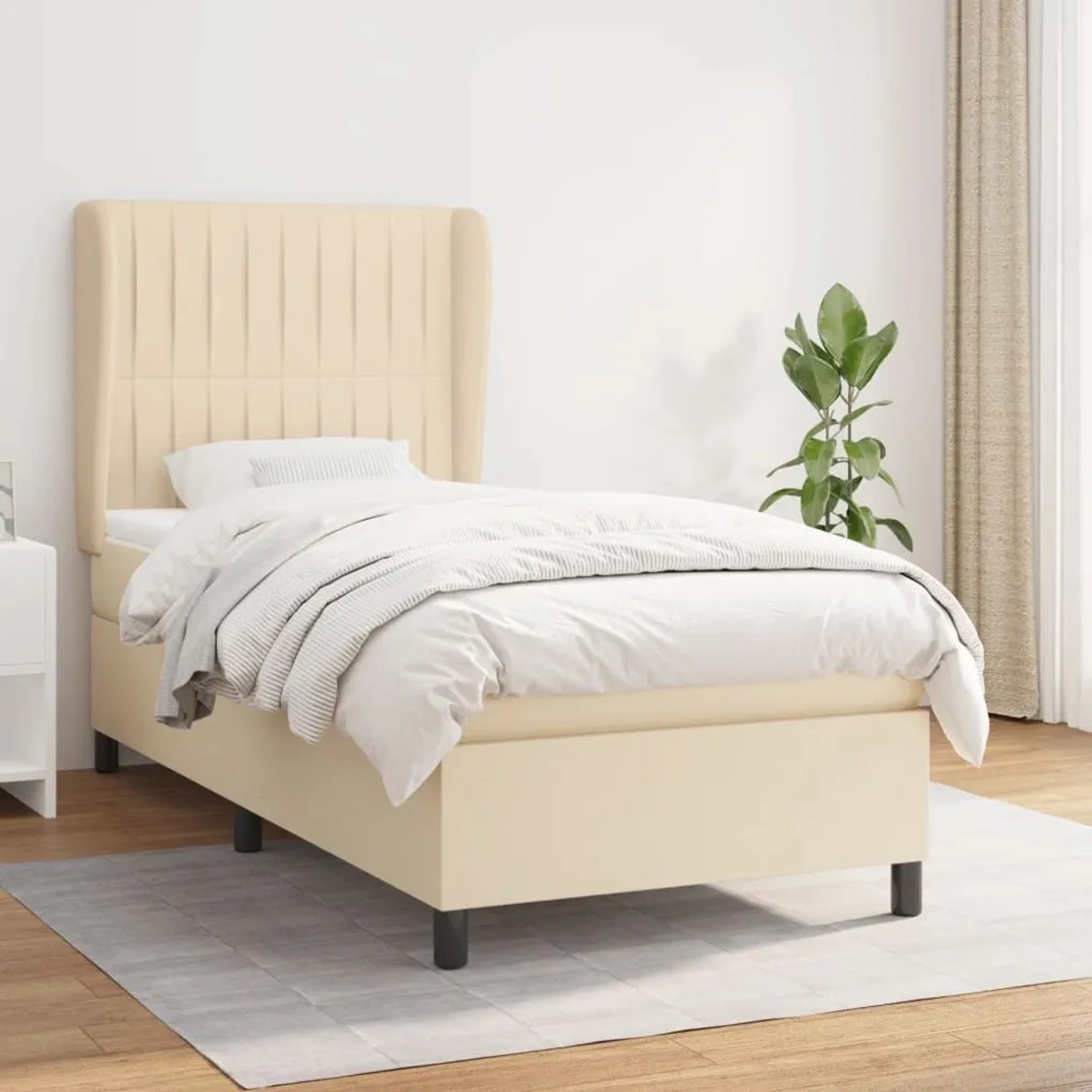 Cremefarbenes Boxspringbett (90x190 cm) mit Matratze und hohem Kopfteil. Stoffbezug.