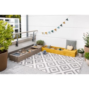 MUDDY BUDDY Sandkasten Flexy Style in Warmgrau und Ocker mit Spielzeug auf einem Balkon.