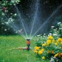 Gardena Comfort Kreisregner Vario auf Spike bewässert Rasenfläche. Regner mit Wasserstrahl im Garten.