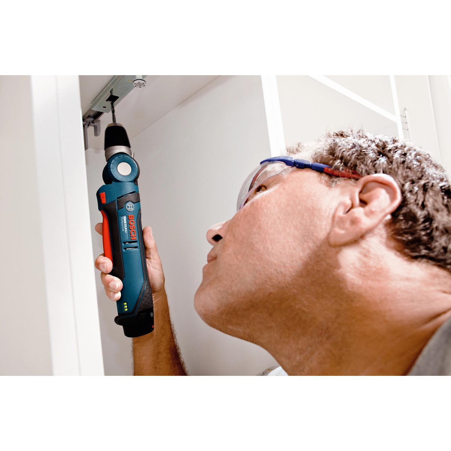 Mann schraubt mit blauem Bosch Professional Akkuschrauber GWB 12V-10 Solo einen Schrank fest.