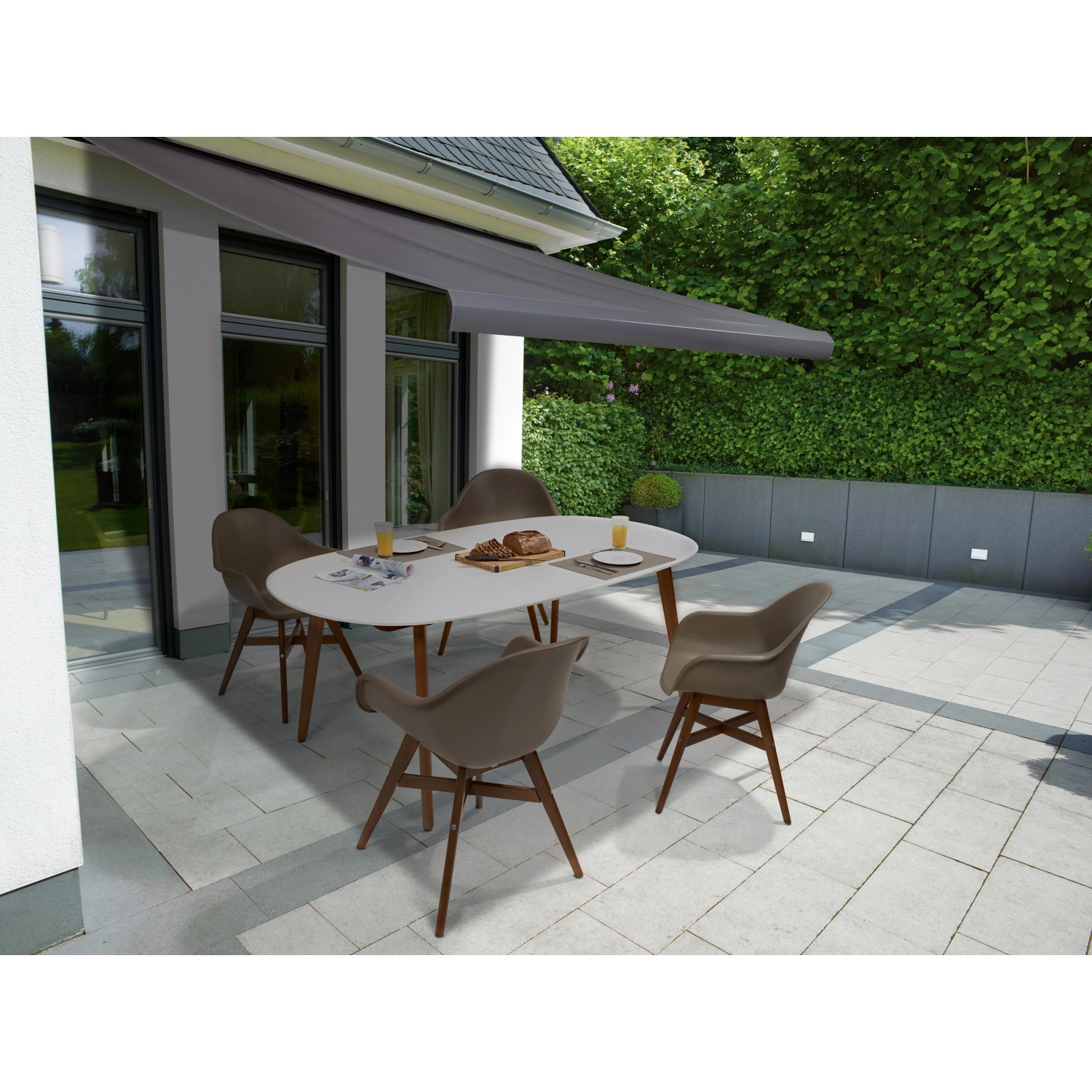 Anthrazitfarbene Kassettenmarkise Bayville 4x2,5m mit LED über einer Terrasse mit Tisch und Stühlen.