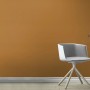 Rasch Vliestapete Tropical House Uni Cognac an Wand, kombiniert mit Stuhl und Tisch.