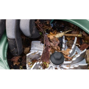 Metalllüfter des Bosch Gartensaugers UniversalGarden Tidy mit Laub verstopft. Hand löst Blockade.