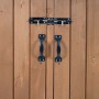 Braune Holztüren der Mülltonnenverkleidung mit schwarzen Griffen und Riegelschlössern für sichere Aufbewahrung.