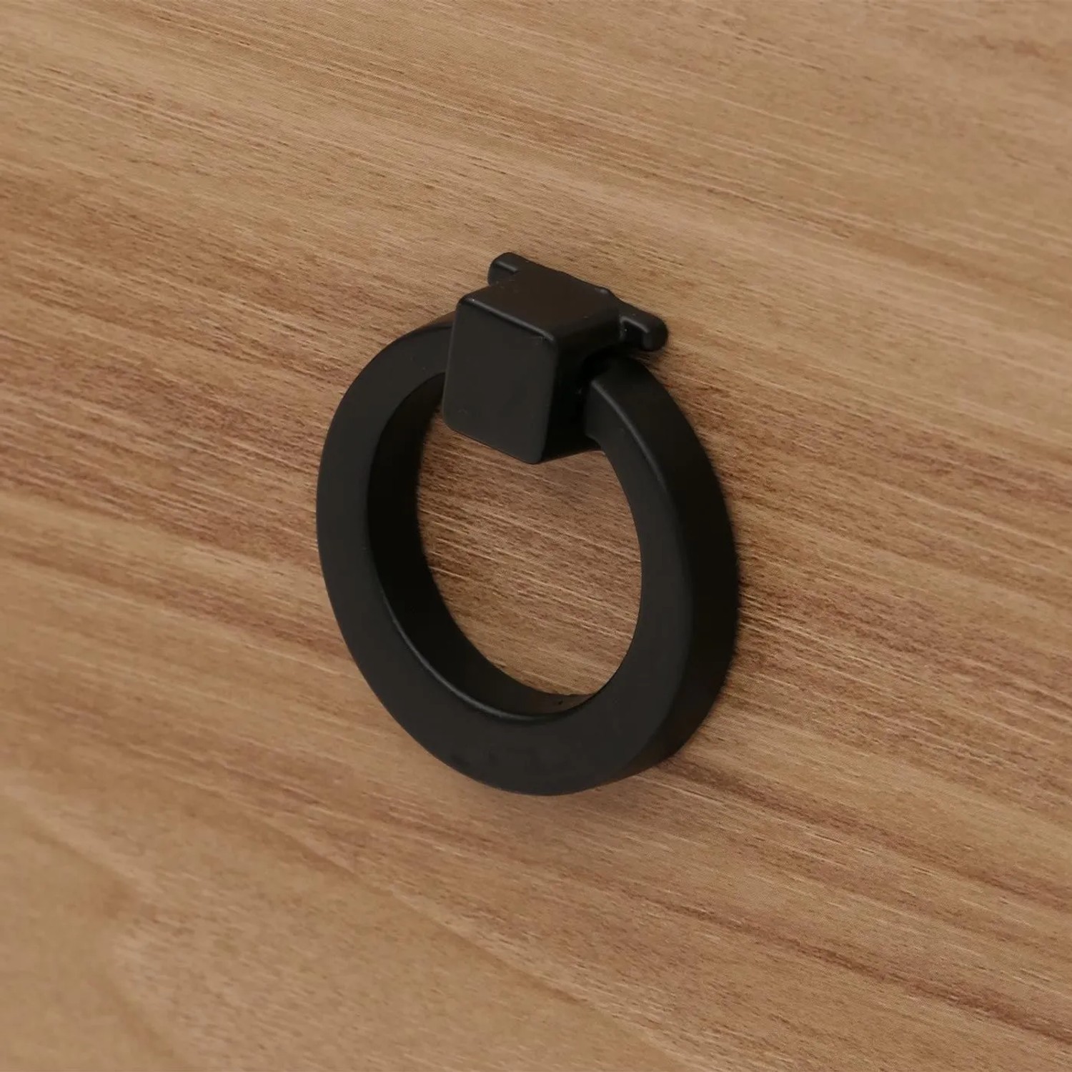 Detailansicht des schwarzen Ring-Griffs auf brauner Holzoberfläche des MCW Wohnzimmerschranks.