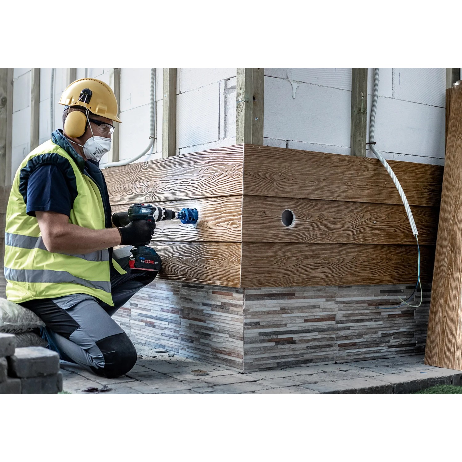 Handwerker bohrt Loch mit Bosch Expert Lochsäge Tough Material Ø 20 mm in Holzverkleidung.