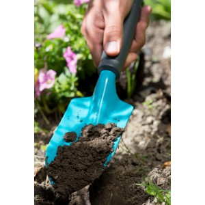 Gardena Blumenkelle Classic im Einsatz: Hand hält Kelle mit Erde im Gartenbeet.