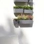 Ecopots Manhattan Wall Hängetopf L, grau, 55 cm, mit Bepflanzung an einer Wand.