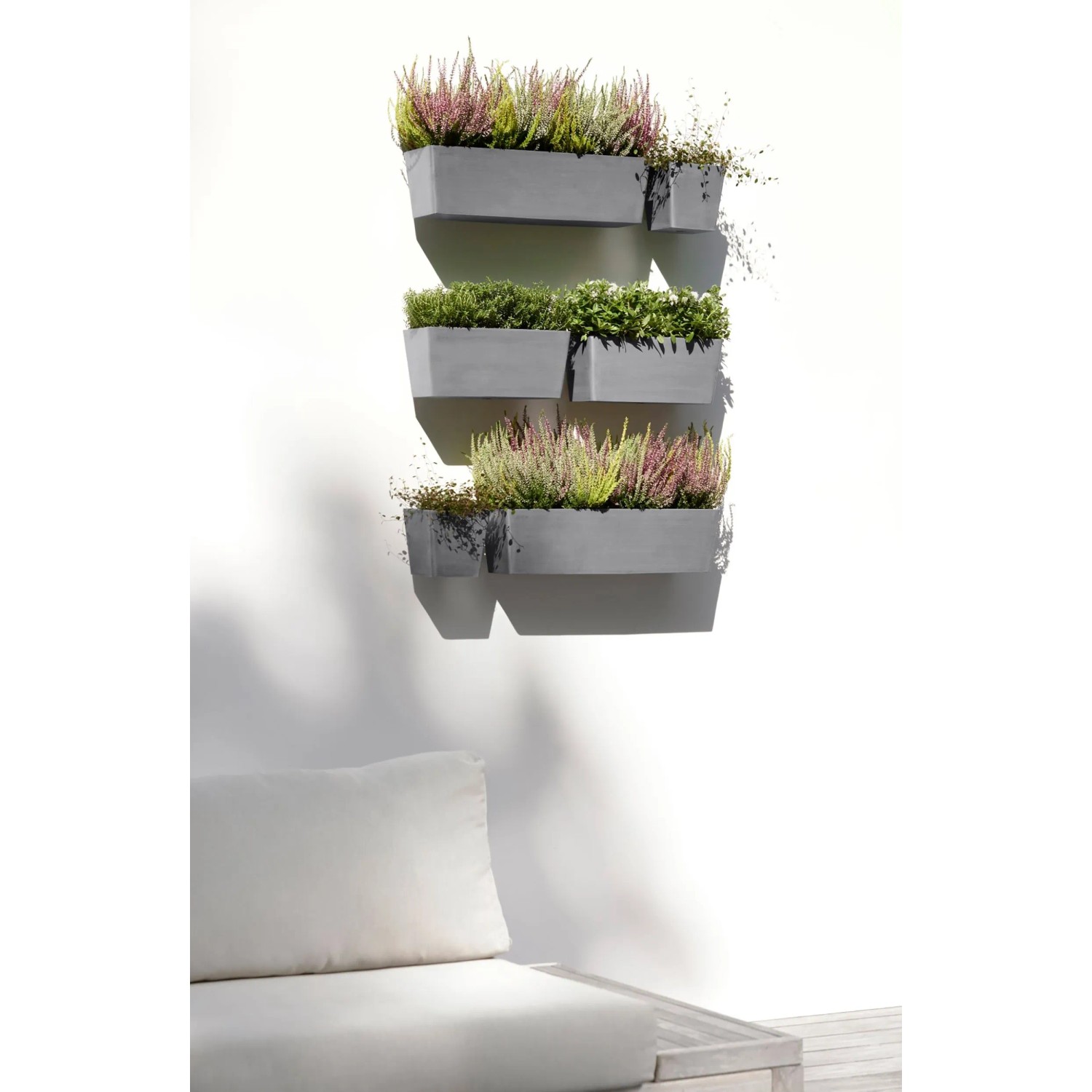 Ecopots Manhattan Wall Hängetopf L, grau, 55 cm, mit Bepflanzung an einer Wand.