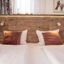Bett mit Egger DecoWall Wandpaneel Namur Fichte Natur als Kopfteil mit Lampen und Steckdosen.