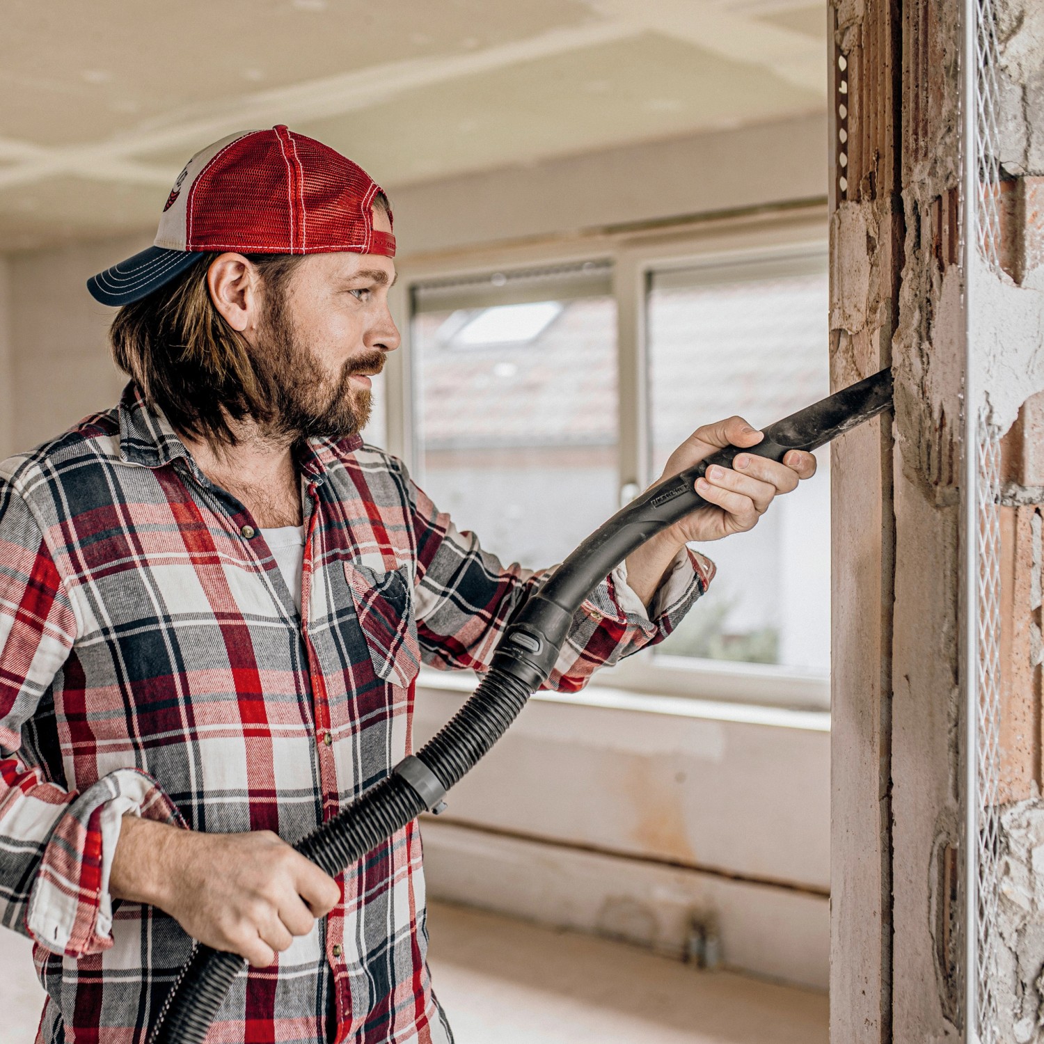 Mann saugt mit Kärcher WD 5 S V-25/5/22 Nass-/Trockensauger eine Wand ab.